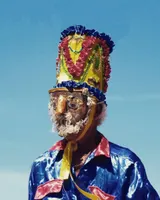 Personaje del sainete con máscara y gorro adornado contra el cielo