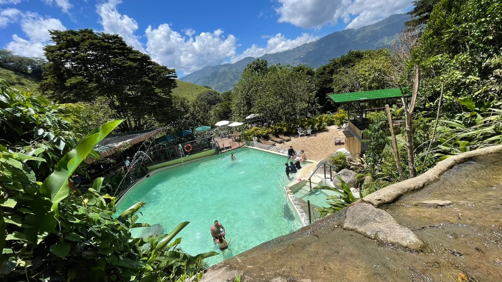 Piscina al aire libre rodeada de vegetación tropical con las montañas del norte antioqueño al fondo